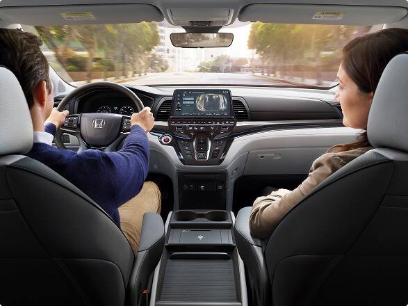 2027 Honda Odyssey Elite family van dashboard, steering wheel, and front cabin with passengers (Minivan).
